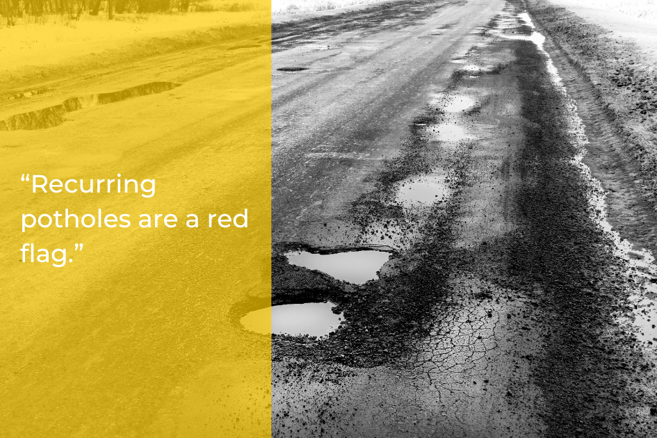 A cracked, uneven road with multiple potholes filled with water on a commercial lot; text on the left reads, “Recurring potholes are a red flag.”.