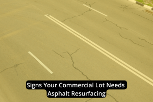 A commercial lot with visible cracks in the pavement and white lane markings; overlaid text reads, "Signs Your Commercial Lot Needs Asphalt Resurfacing." These signs indicate it's time for asphalt resurfacing to maintain safety and curb appeal.