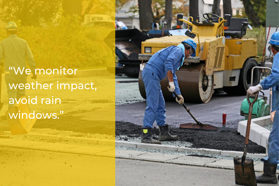 Two construction workers in blue uniforms lay asphalt on a road using shovels, with a steamroller in the background and construction equipment nearby, ensuring quality asphalt repair for property owners in Central Texas.